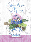 Elegant greeting card for Mom featuring a white teacup overflowing with vibrant blue and pink violet flowers against a rustic white wood background, with 'Especially for Mom' text.