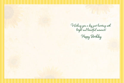 Inside of a birthday greeting card with faded sunflower illustrations and the message 'Wishing you a day just bursting with bright and beautiful moments! Happy Birthday' in green script, framed by yellow stripes.
