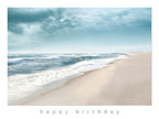 Front of a tranquil beach greeting card featuring gentle ocean waves, soft sandy shore, and a serene blue sky, with 'happy birthday' printed below.