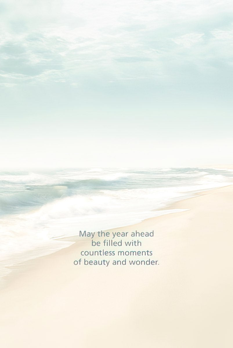 Inside view of a peaceful beach-themed greeting card showing the ocean waves and sand, with the heartfelt message 'May the year ahead be filled with countless moments of beauty and wonder.'