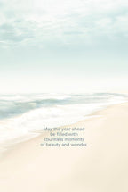 Inside view of a peaceful beach-themed greeting card showing the ocean waves and sand, with the heartfelt message 'May the year ahead be filled with countless moments of beauty and wonder.'