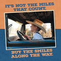 Smiling boy in cowboy hat driving vintage truck, inspiring quote magnet 'It's not the miles that count, but the smiles along the way' on an orange and blue background.