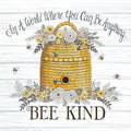A decorative magnet featuring a golden beehive surrounded by yellow and white flowers, green leaves, and flying bees, set against a white rustic wooden background. The text reads: 'In A World Where You Can Be Anything... BEE KIND' in elegant script and bold serif fonts.