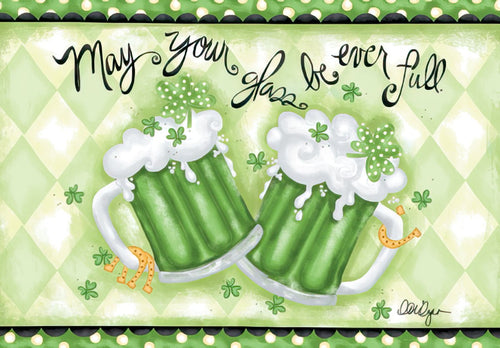 Front of a festive St. Patrick's Day greeting card featuring two frothy green beer mugs overflowing with foam and clovers, surrounded by lucky shamrocks and golden horseshoe accents, against a light green argyle background with the cheerful message 'May your glass be ever full.'