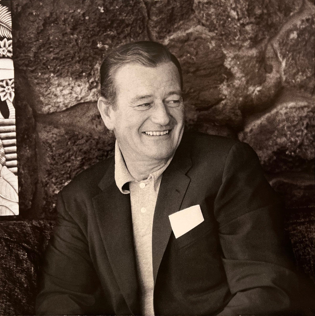 John Wayne in a casual blazer and polo shirt, smiling, a timeless image for the John Wayne collector's calendar.