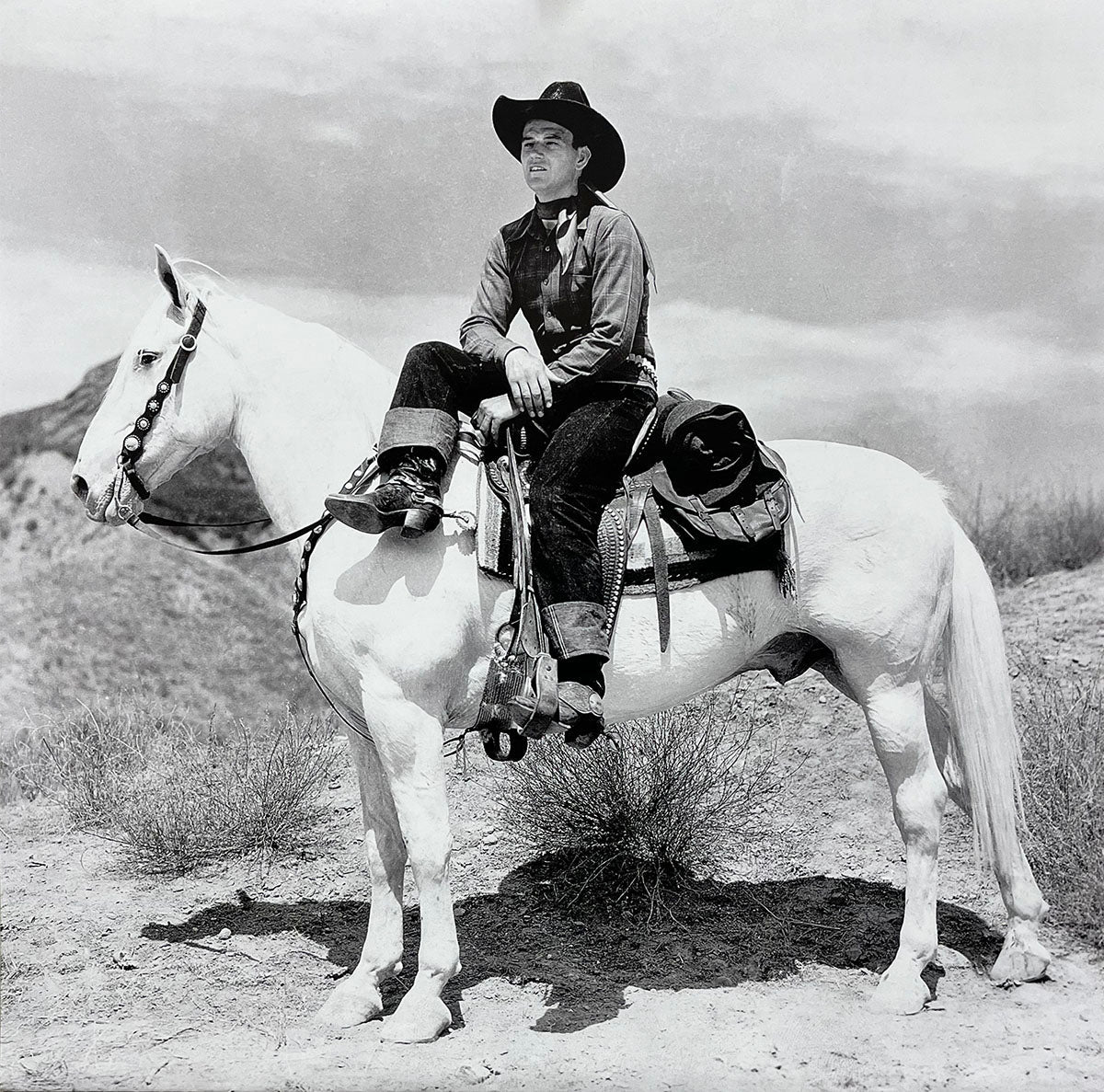 Young John Wayne looking confident, sitting atop a white horse in a vast western landscape, featured in the calendar.