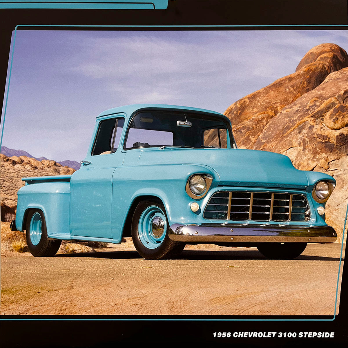 A light blue 1956 Chevrolet 3100 Stepside pickup truck, gleaming on a dirt road in a rocky desert environment under a bright sky, showcasing its vintage curves.