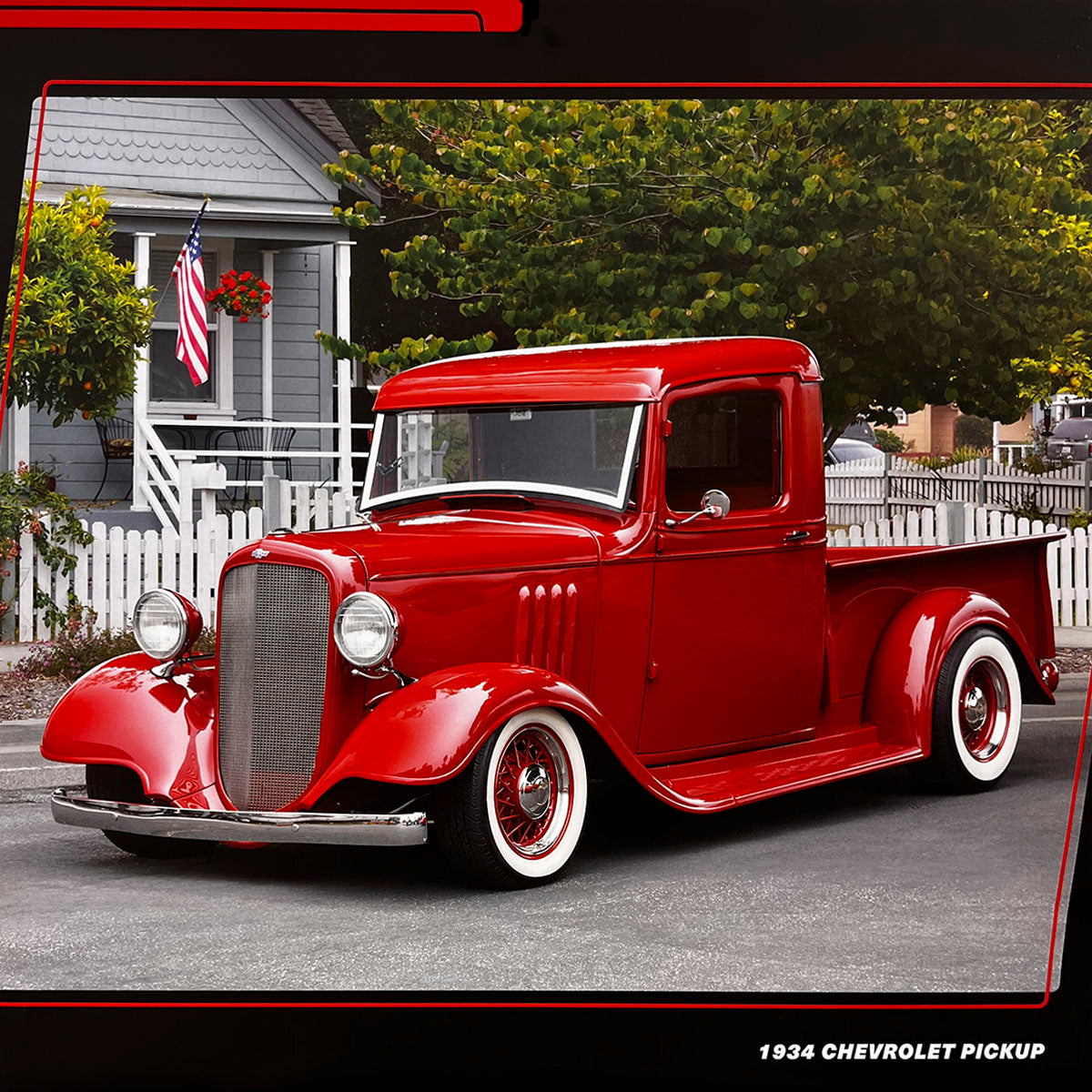 A classic red 1934 Chevrolet Pickup truck with white wall tires, parked on a street in front of a white picket fence and a charming house, evoking nostalgia.