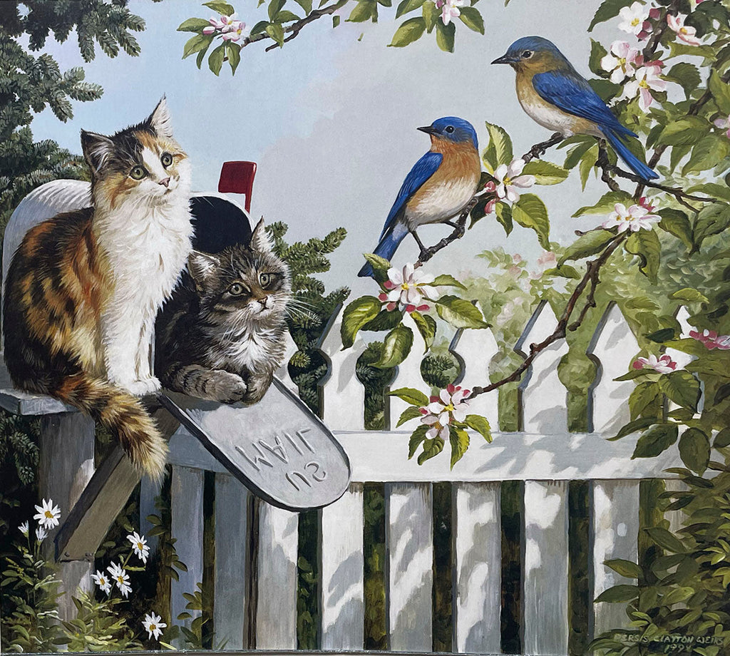 A calico cat perched on a country mailbox with a small tabby kitten inside, observing two bluebirds on a branch next to a white picket fence in a spring garden.
