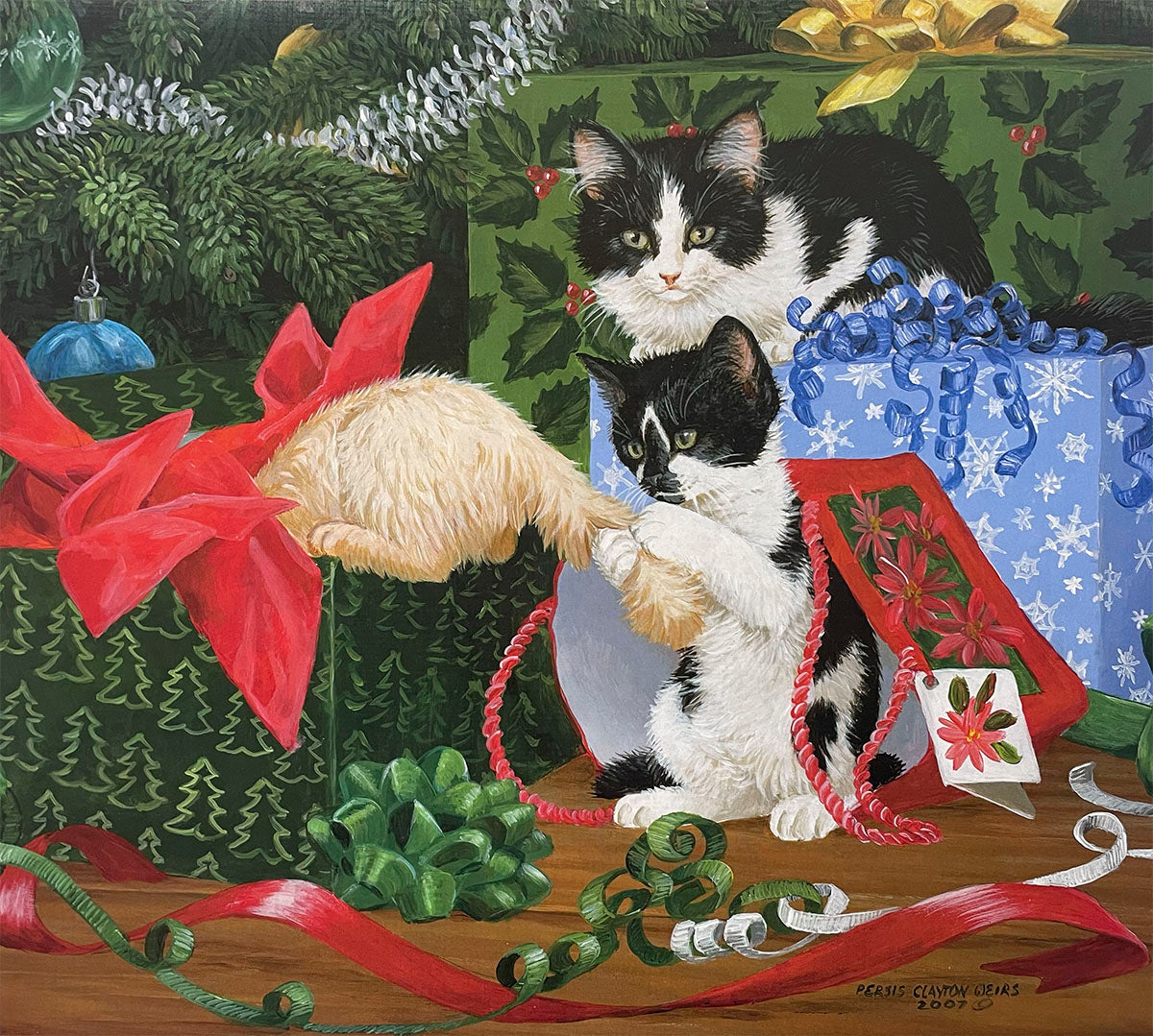 Two mischievous black and white tuxedo kittens playing amongst festive Christmas presents and colorful ribbons under a green decorated Christmas tree.
