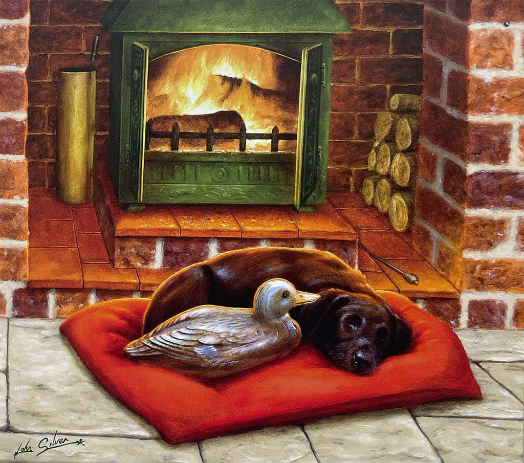 A cozy scene with a sleeping black Labrador Retriever curled up on a red cushion next to a duck decoy, in front of a warm, crackling fireplace with brick surrounds.