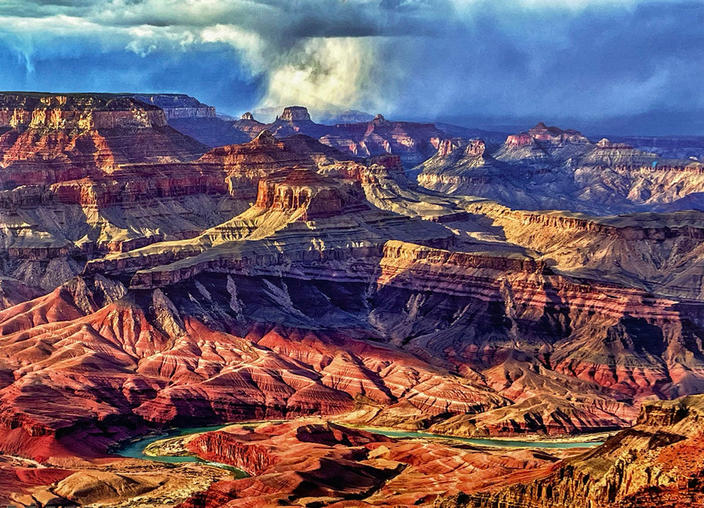 Grand Canyon landscape featuring the vivid green Colorado River snaking through deep red and multi-colored canyons under a partly cloudy sky with sun rays, a breathtaking view for a wall calendar.