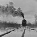 Powerful steam locomotive no. 109 advancing through a snow-covered landscape, emitting thick smoke, vintage black and white railroad photography, winter train scene, classic American railway.