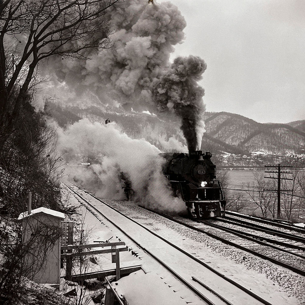 Historic steam locomotive roaring through a snowy, mountainous landscape, emitting a large plume of smoke and steam, dynamic winter train scene, railway adventure.
