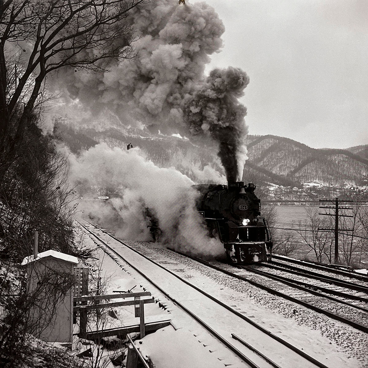 Historic steam locomotive roaring through a snowy, mountainous landscape, emitting a large plume of smoke and steam, dynamic winter train scene, railway adventure.