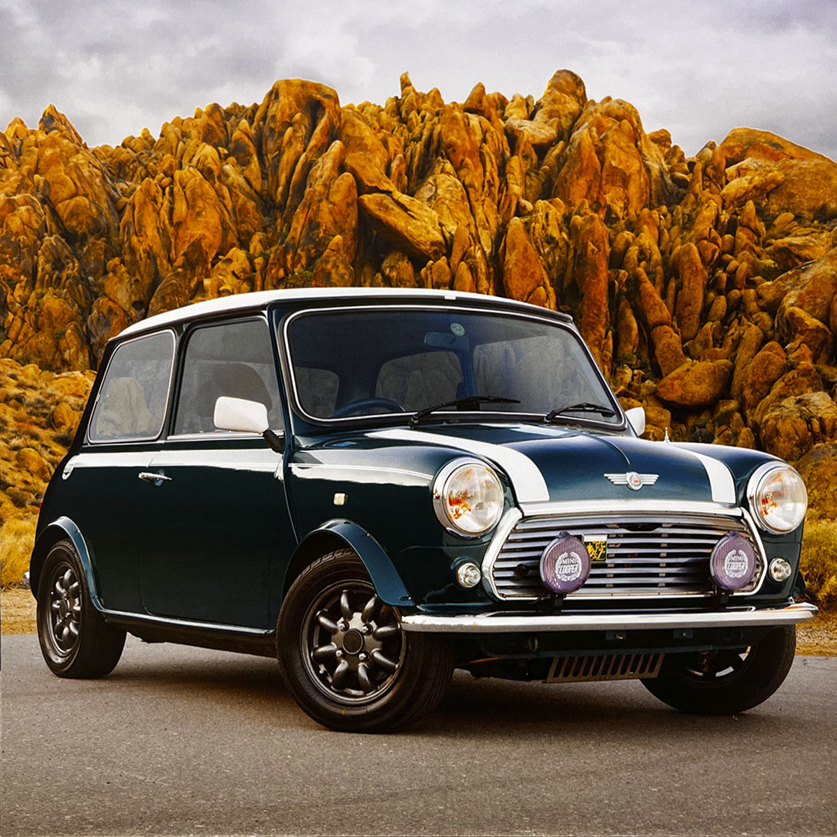A pristine dark green 1971 Mini Cooper with white racing stripes, parked on a road against a backdrop of golden rocky hills, highlighting its classic design and adventurous spirit.