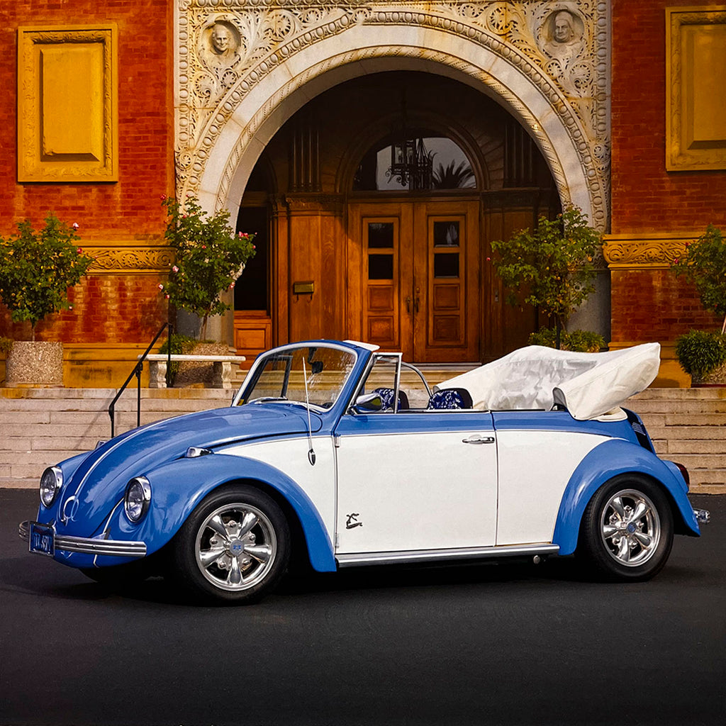 A vibrant blue and white 1968 Volkswagen Beetle convertible with its top down, parked in front of a grand architectural building, radiating timeless charm and open-road freedom.