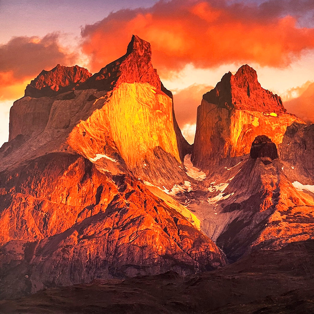 Dramatic sunset over rugged mountain peaks in a wall calendar, showcasing vibrant orange and red clouds illuminating the jagged rock formations. SEO: sunset mountains, dramatic landscape, fiery sky, rugged peaks, nature photography calendar.