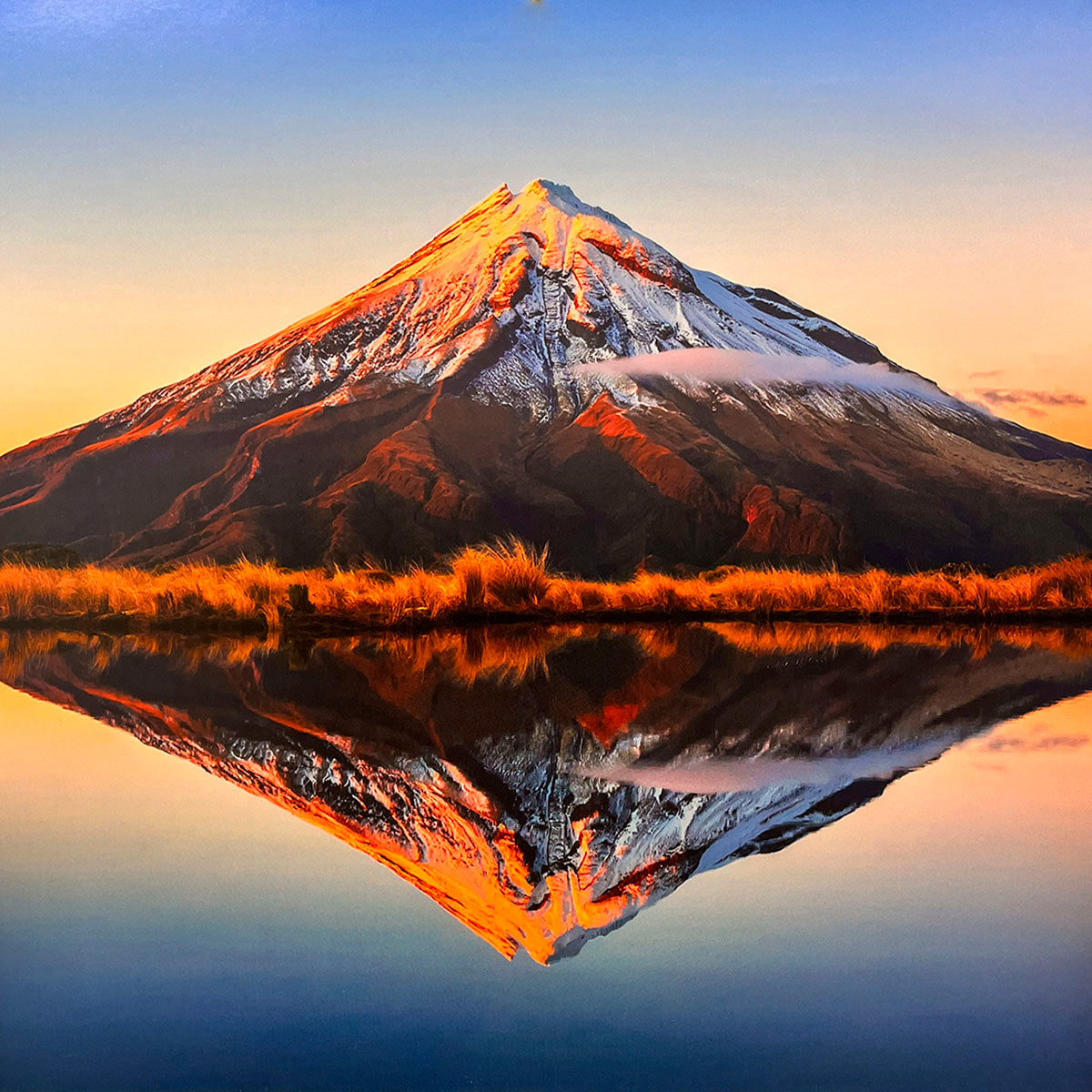 Stunning mountain reflection for wall calendar, showing a perfectly symmetrical reflection of a snow-capped peak in a calm body of water at sunrise or sunset, with golden grasses. SEO: mountain reflection, tranquil lake, snow-capped peak, sunrise sunset, nature calendar.