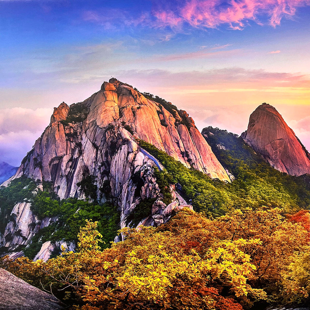 Vibrant sunset over a range of colorful, rugged mountains for wall calendar, with rich green and warm autumn foliage in the foreground, under a pastel-hued sky. SEO: colorful mountains, autumn foliage, vibrant sunset, rocky peaks, scenic calendar.