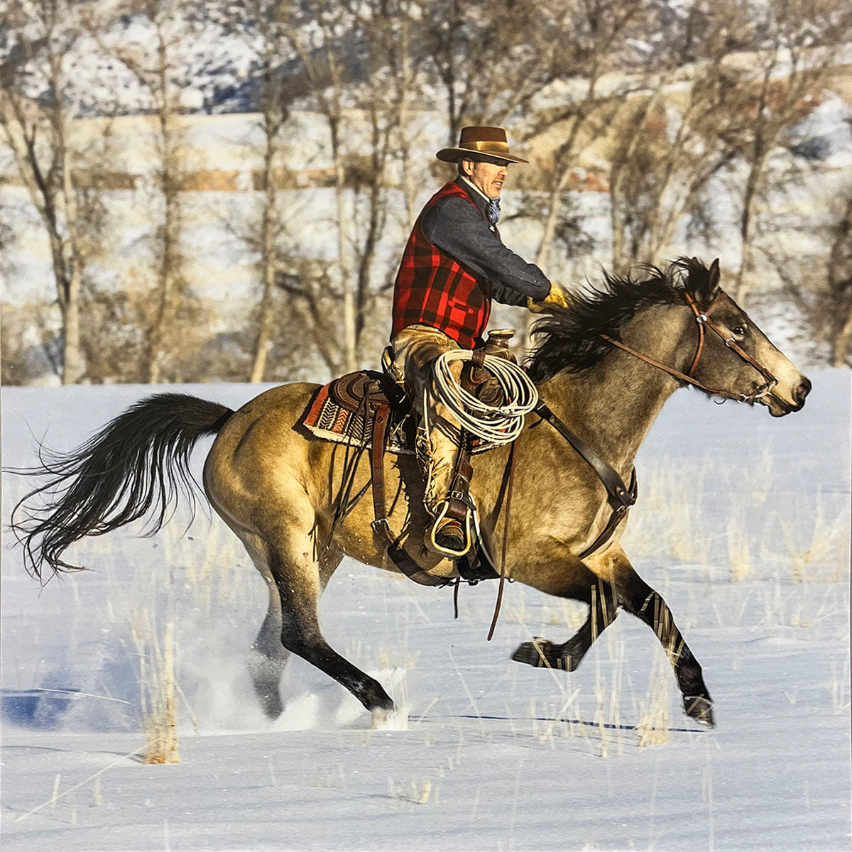 Dynamic image of a cowboy on a horse galloping through a snowy field, depicting rugged Western winter life for a wall calendar.