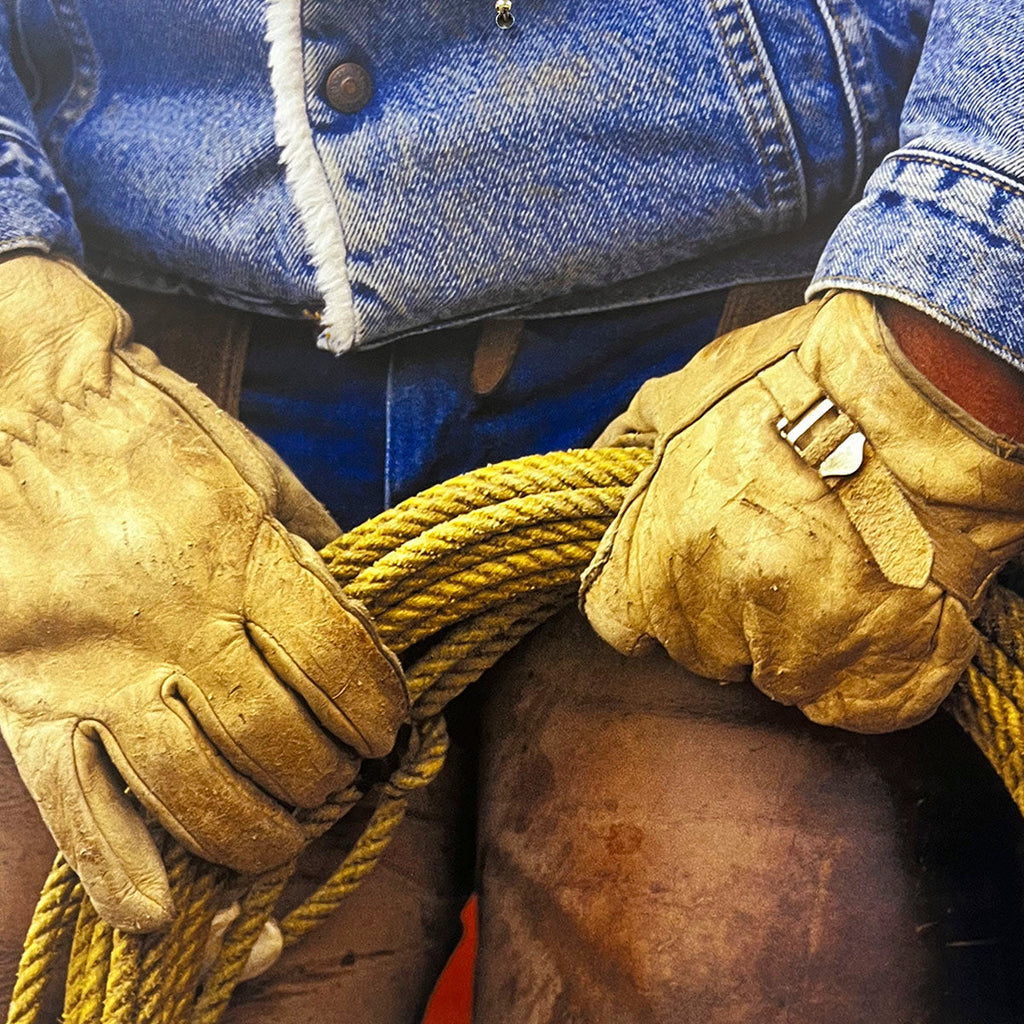 Close-up detail of gloved cowboy hands expertly coiling a yellow rope, showcasing authentic Western gear and ranch work for a calendar.