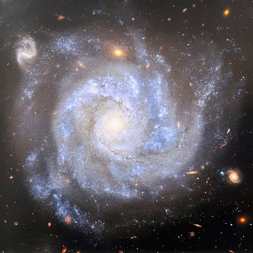 Majestic spiral galaxy with prominent bright blue arms swirling around a glowing yellowish central core against the dark expanse of space.