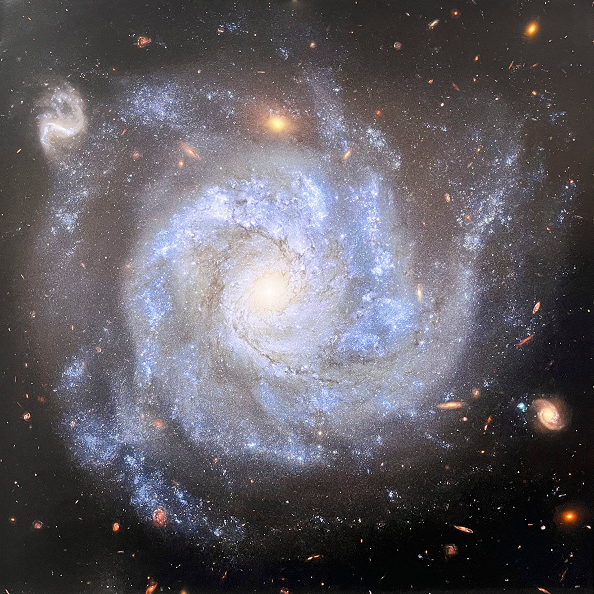 Majestic spiral galaxy with prominent bright blue arms swirling around a glowing yellowish central core against the dark expanse of space.