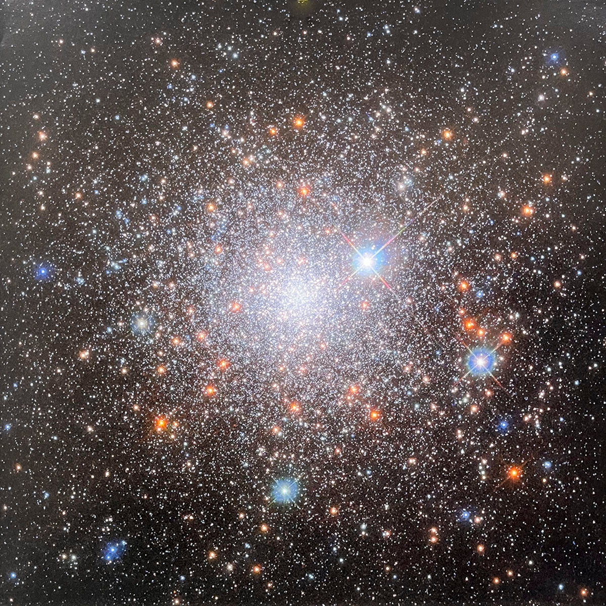 Densely packed globular cluster of myriad stars, appearing as a brilliant, glowing ball of light in the dark cosmos.