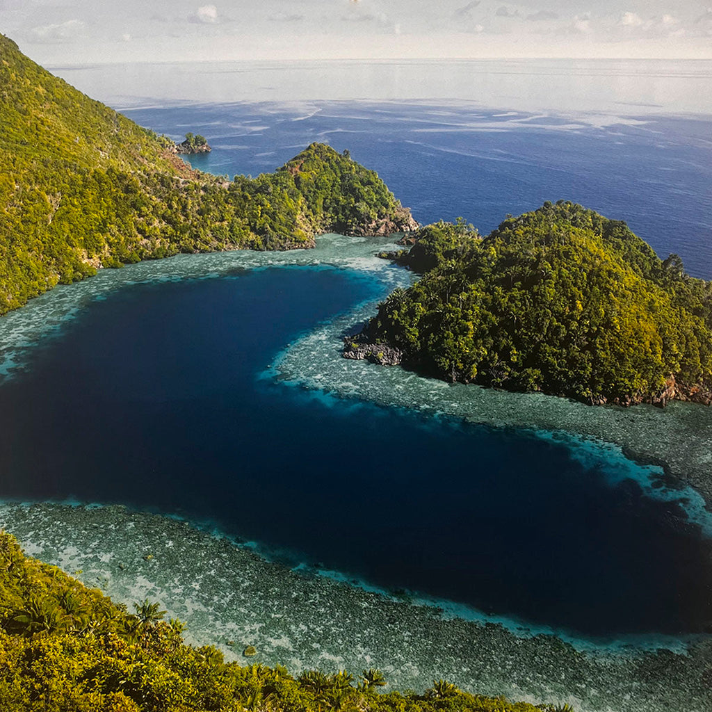 Captivating aerial view of a vibrant tropical lagoon with turquoise coral reefs, deep blue ocean, and lush green islands. Excellent for a travel destination calendar, coastal landscapes, ocean photography.