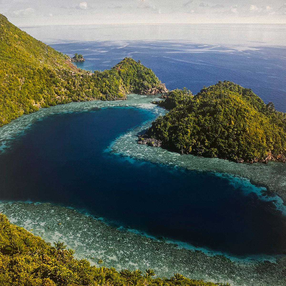 Captivating aerial view of a vibrant tropical lagoon with turquoise coral reefs, deep blue ocean, and lush green islands. Excellent for a travel destination calendar, coastal landscapes, ocean photography.