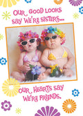 Two adorable baby girls wearing colorful flower leis and stylish sunglasses, dressed in pink and yellow bikinis, sitting on a fluffy white rug with the playful text 'Our good looks say we're sisters... Our hearts say we're friends.' Perfect for a friendship magnet.