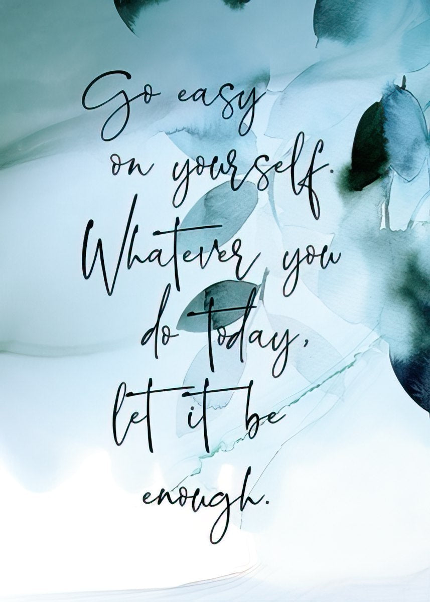 A close-up of an inspirational magnet with the quote 'Go easy on yourself. Whatever you do today, let it be enough.' in elegant black script on a soft blue and green watercolor background.