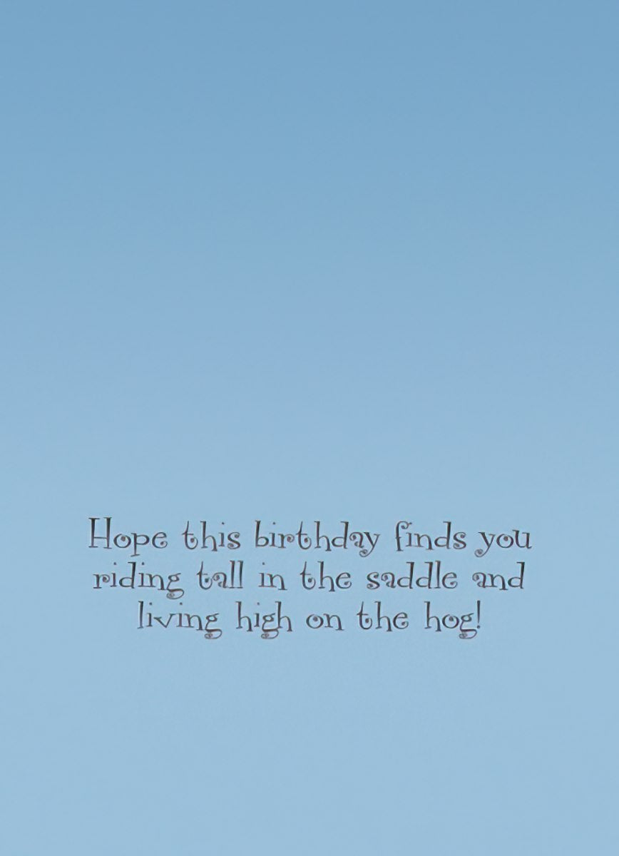 Inside text of funny birthday card with pig pun, printed on a light blue background: 'Hope this birthday finds you riding tall in the saddle and living high on the hog!'