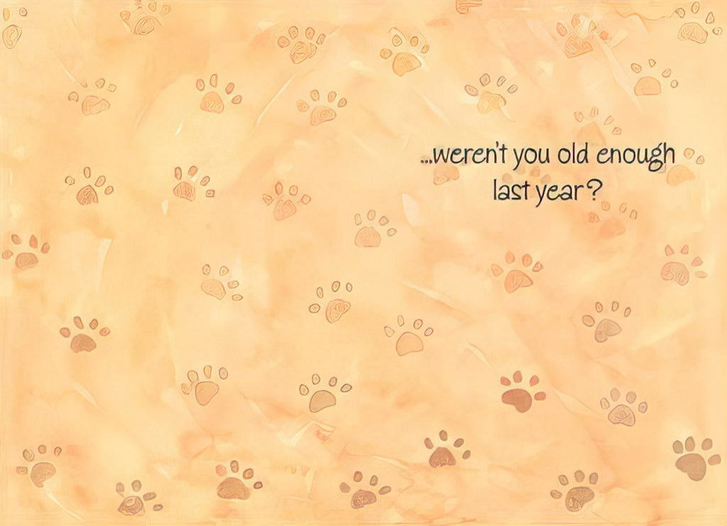 Inside of a humorous greeting card, light orange background with subtle paw print patterns, featuring the witty message '...weren't you old enough last year?' in brown script font.
