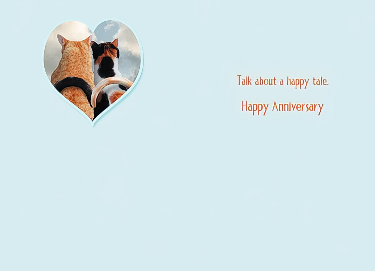 Open anniversary greeting card with two cats in a heart frame on the left and 'Talk about a happy tale. Happy Anniversary' text on the right.