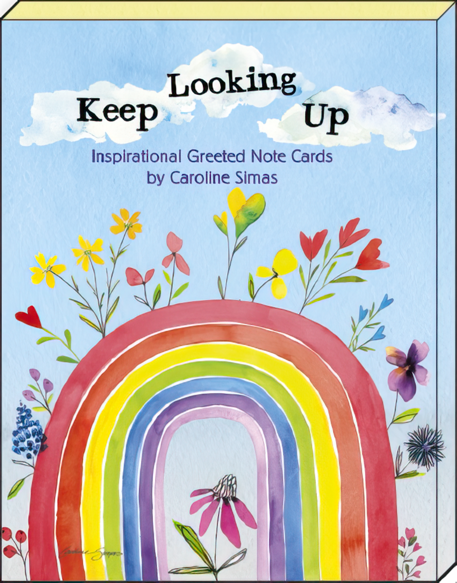 Close-up of an inspirational 'Keep Looking Up' greeting card by Caroline Simas, showcasing a vibrant rainbow, blooming flowers, and fluffy clouds against a blue sky, designed to bring hope.