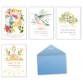 Assortment of four watercolor religious greeting card fronts featuring floral designs, hummingbirds, and scripture verses, alongside a light blue envelope.