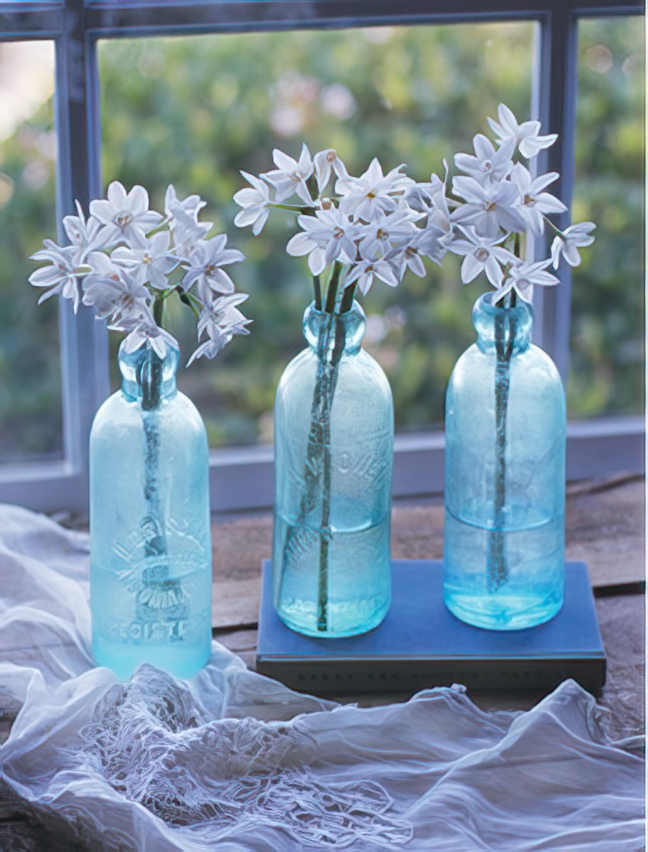 Three blue glass jars with flowers