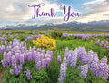 Front of a thank you greeting card featuring a vibrant mountain meadow with purple lupines and yellow wildflowers under a blue sky, with 'Thank You' scripted in elegant purple font.
