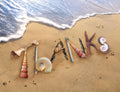 Premium greeting card set featuring 'THANKS' spelled out with natural seashells, a starfish, and beach elements on a sandy shore with gentle ocean waves. Perfect for expressing heartfelt gratitude.