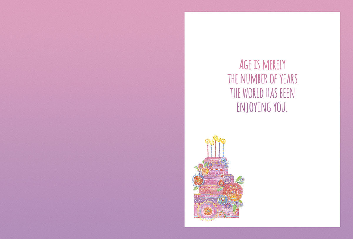 Open heartfelt greeting card interior with a colorful floral cake illustration and the message "AGE IS MERELY THE NUMBER OF YEARS THE WORLD HAS BEEN ENJOYING YOU." on a light purple background.