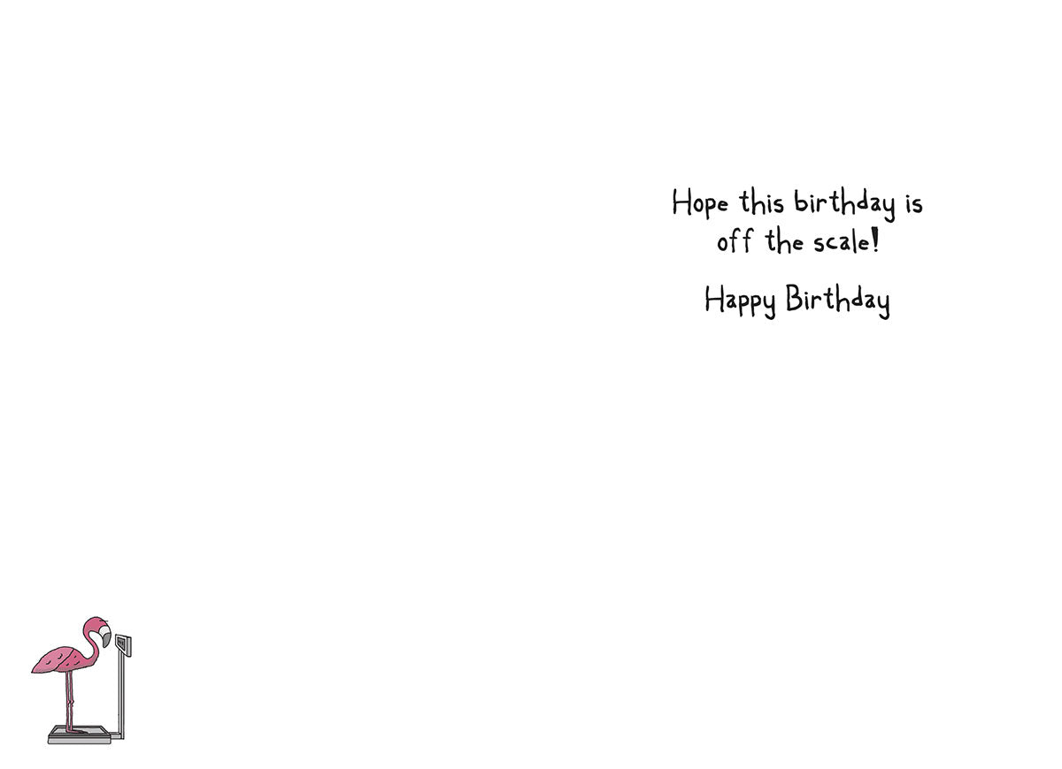 Inside of a funny birthday card, displaying the handwritten message "Hope this birthday is off the scale! Happy Birthday". A small, charming illustration of a pink flamingo standing on a weight scale is visible in the bottom left corner, reinforcing the card's witty theme.