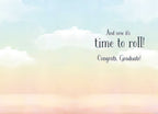 Inside of a congratulatory greeting card showing a light blue and peach sky background with clouds, and the celebratory message 'And now it's time to roll! Congrats, Graduate!' in elegant script.
