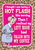 Funny birthday card for women featuring a cartoon older woman in a bathrobe with curlers, pointing, inside a bright pink speech bubble with leopard print background. Text humorously describes a 'hot flash' which is actually her left boob falling into coffee.