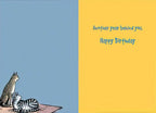 Inside view of a humorous greeting card with a calming blue left panel featuring the same cats, and a vibrant yellow right panel displaying the message 'Another year behind you. Happy Birthday' in stylish blue script.