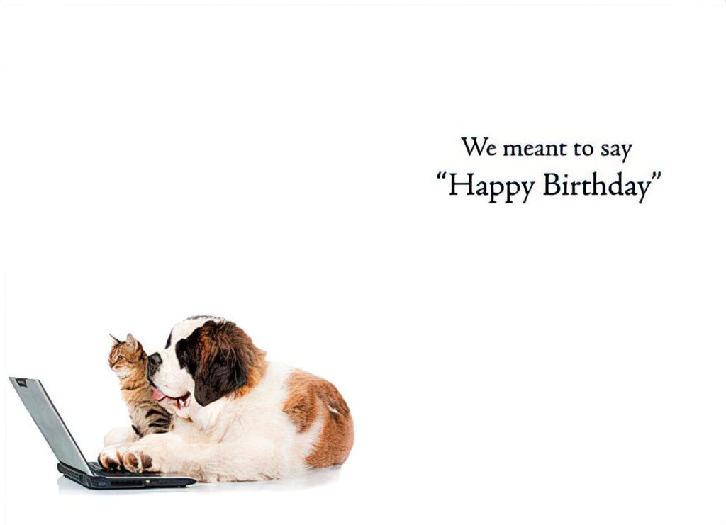 A humorous greeting card showing a cute cat playfully nuzzling a large dog who is looking at a laptop, with the text 'We meant to say "Happy Birthday"' implying a belated or funny message.