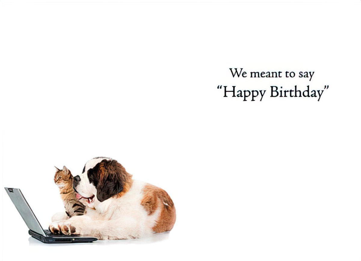 A humorous greeting card showing a cute cat playfully nuzzling a large dog who is looking at a laptop, with the text 'We meant to say "Happy Birthday"' implying a belated or funny message.