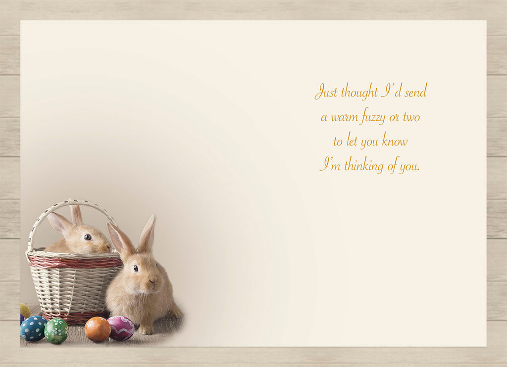 Inside of a heartwarming message card for springtime, showing the same charming scene of two fluffy bunnies and colorful eggs. The gentle sentiment reads: 'Just thought I'd send a warm fuzzy or two to let you know I'm thinking of you.'