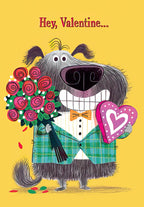 Front of a cute Valentine's Day greeting card featuring a fluffy grey dog wearing a green plaid suit jacket and an orange bow tie, holding a vibrant bouquet of red roses and a pink heart-shaped candy box on a yellow background with the text 'Hey, Valentine...'